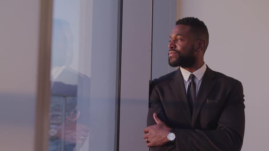 A man stands by the window looking out
