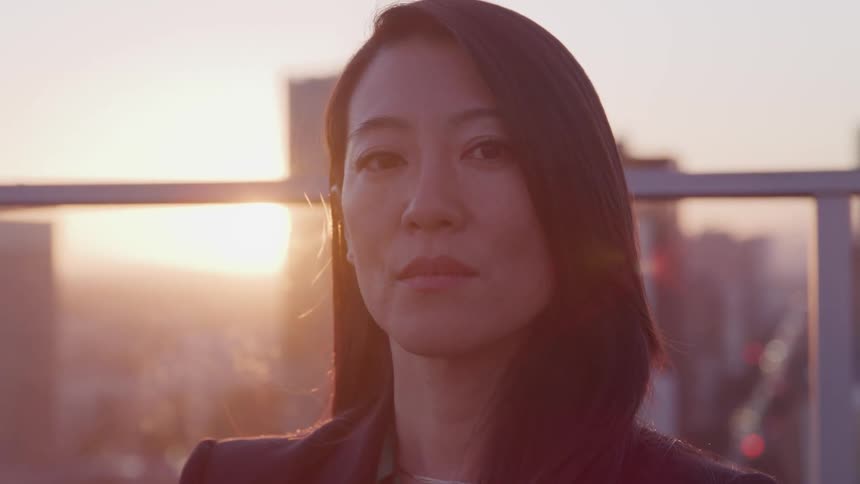 A woman is standing on a balcony in an urban city