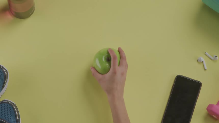 A hand grabbing anapple from a table