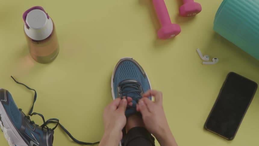 A woman ties her running shoe as she prepares to exercise