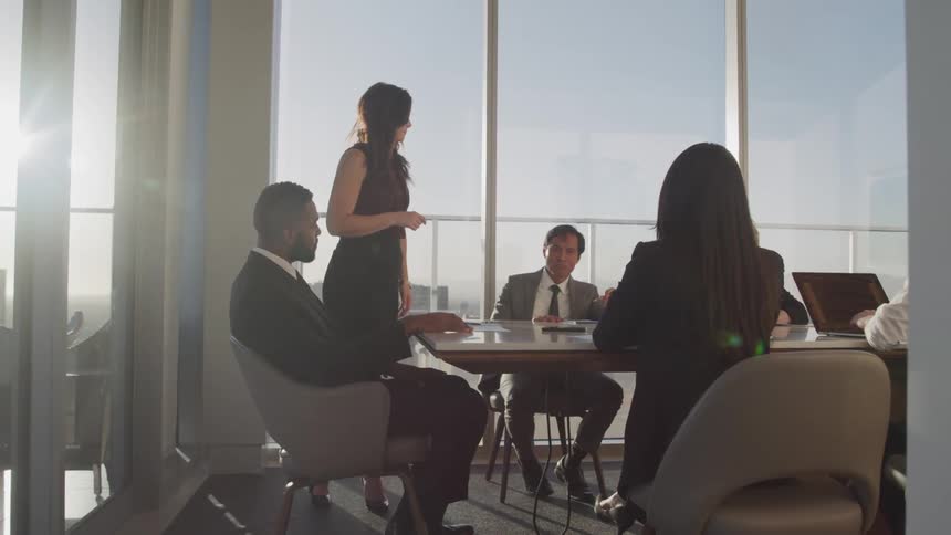 Business people sit at a long table conduct a meeting in conference room