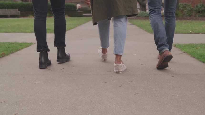 Three friends are walking on a sidewalk together