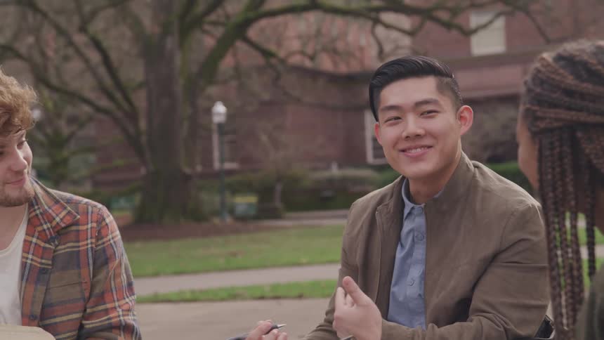A group of young university students sit together outside while conversing
