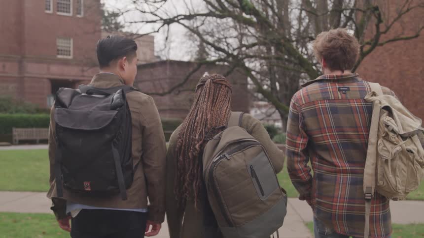 Three students walk towards the building on campus