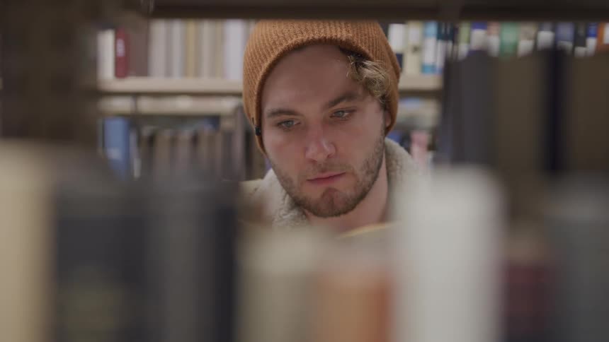 A man opens and reads a book in the library