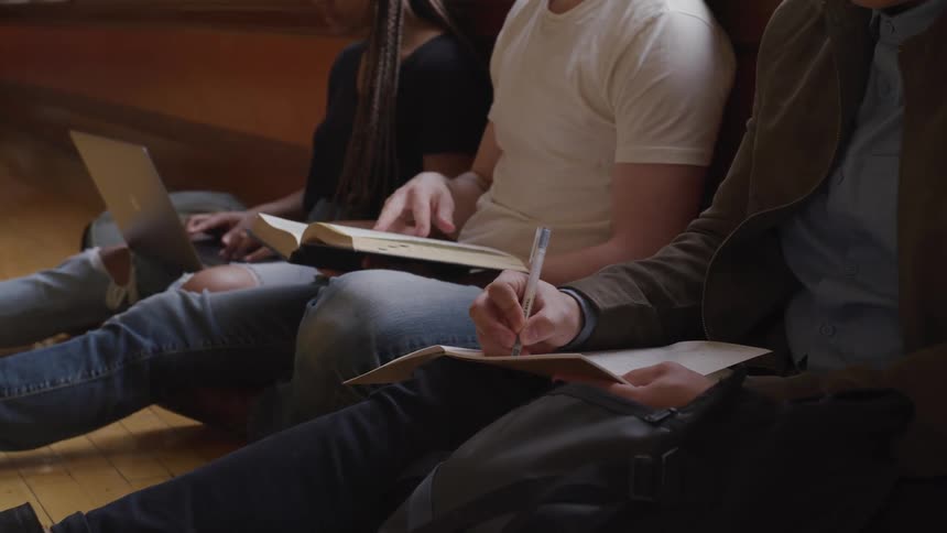 Three friends sit on a floor and do schoolwork