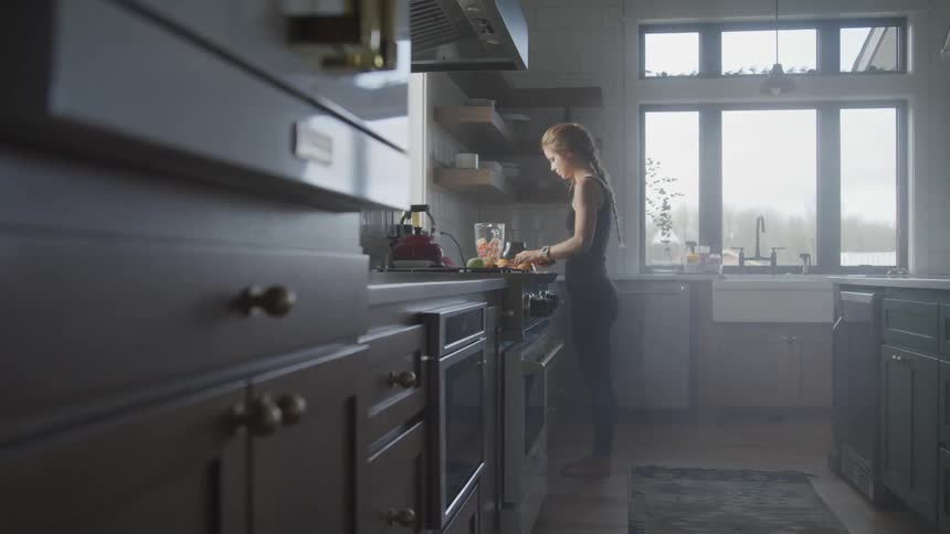 Young woman cuts vegetables in a kitchen