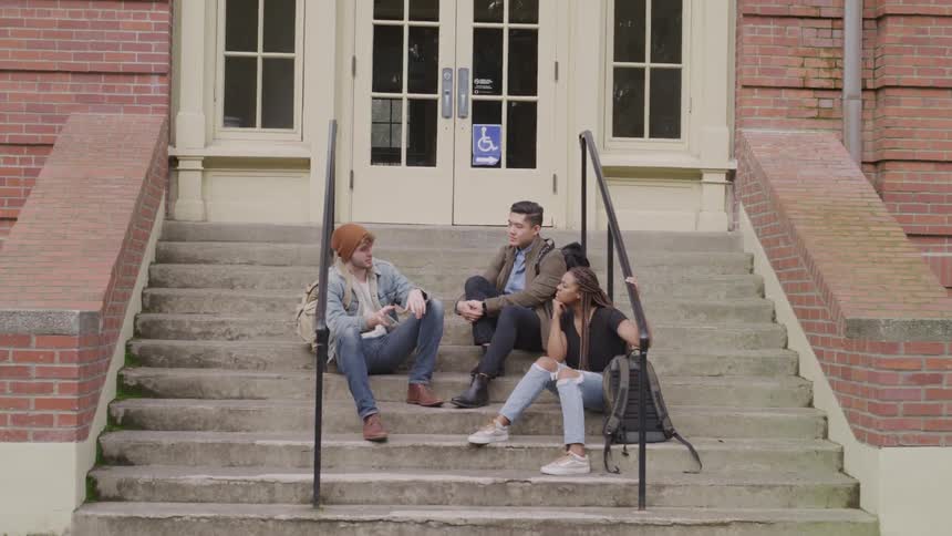 Three students have a conversation on the school steps