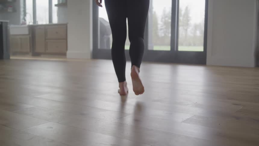 Walking barefoot on hardwood floor towards patio door