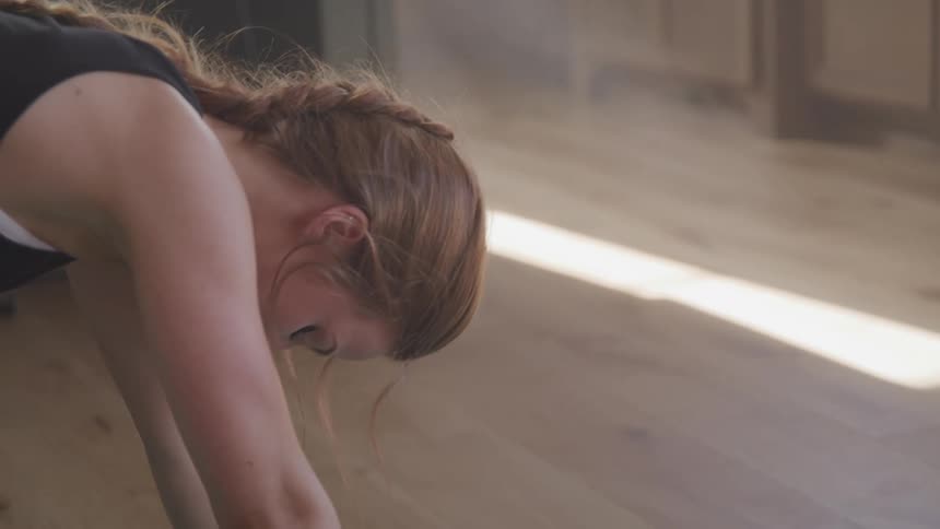 A woman is stretching on a yoga mat indoors
