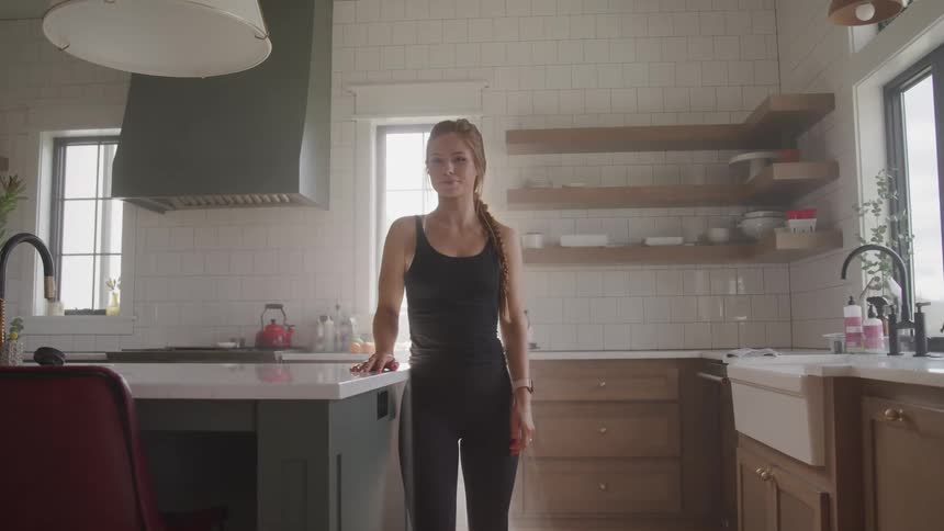 A woman is standing in her kitchen