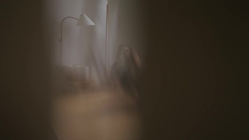 A teenage girl sits on the floor of her bedroom and looks at herself in the mirror