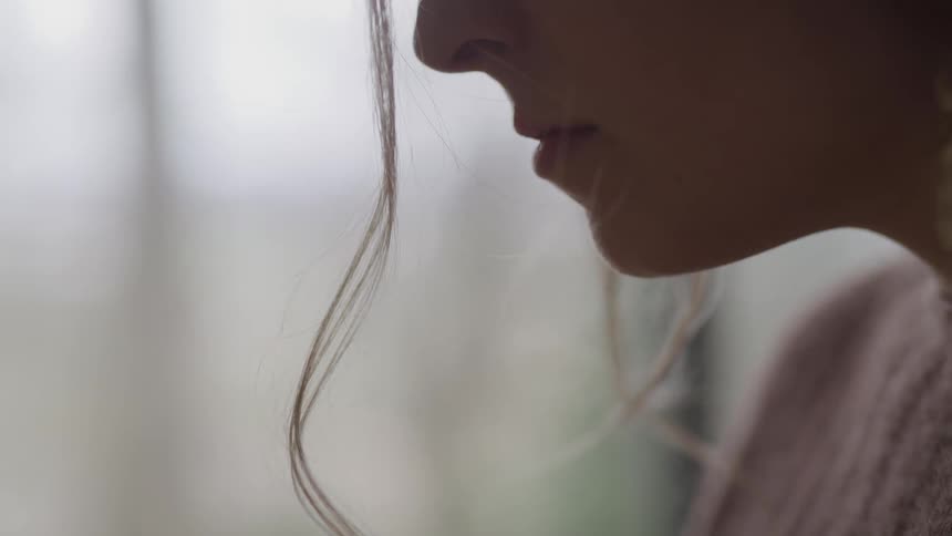 Close up of the lips and nose on a womans face sitting in a room