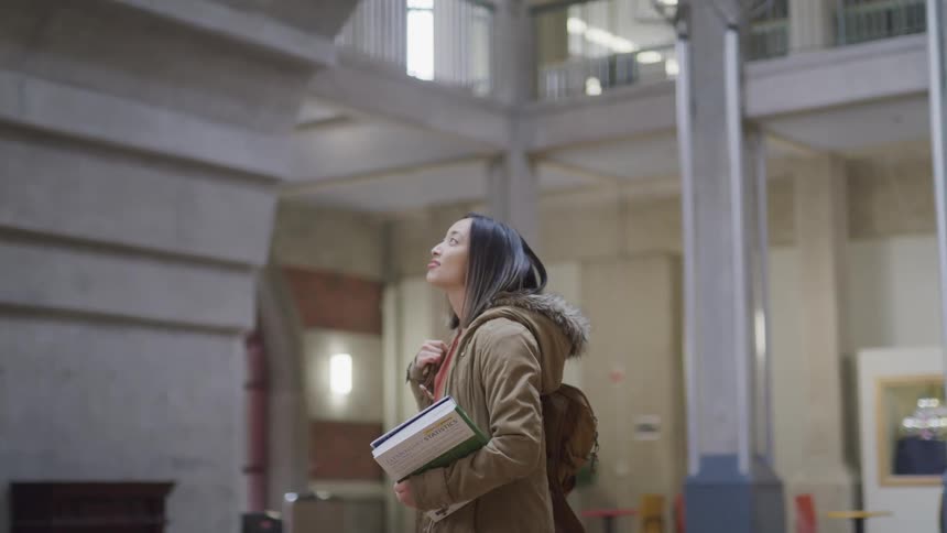 An asian female standing in a building staring at the ceiling