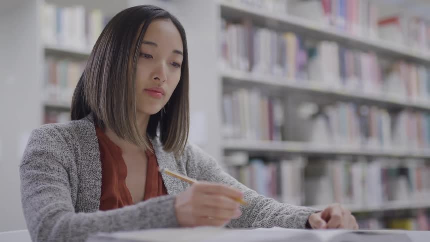Asian teenage girl with straight hair studies in the library