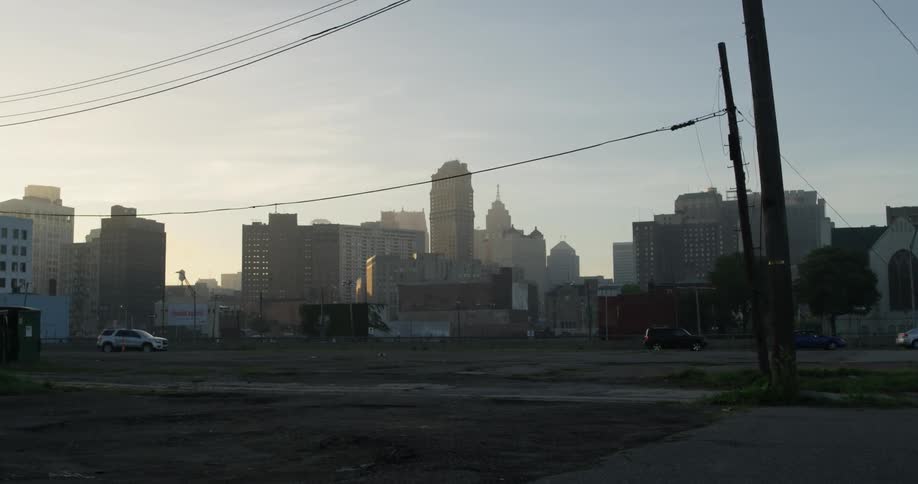 The sun rises behind a city as a vehicle passes by