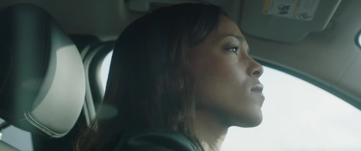 A woman is driving a car while seemingly looking for something