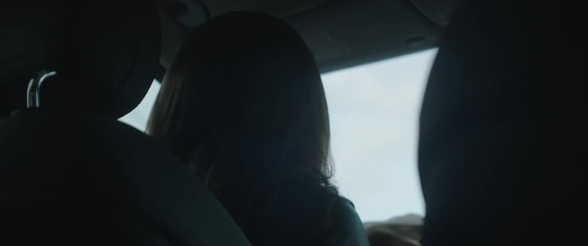 A woman is driving and looking in the backseat