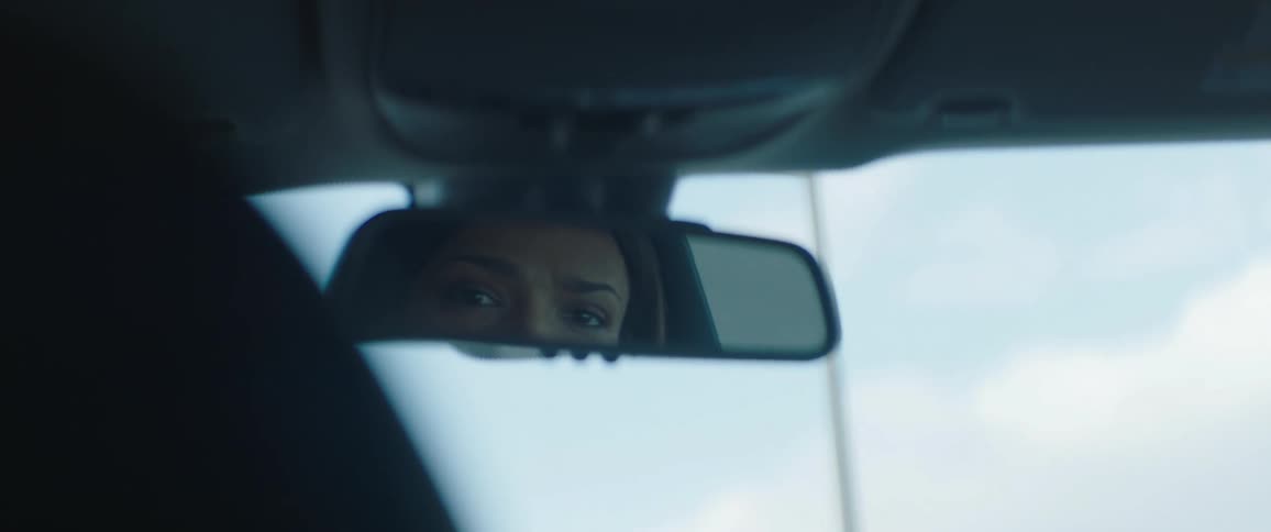 A view of a woman's searching eyes in the rear view mirror of a car