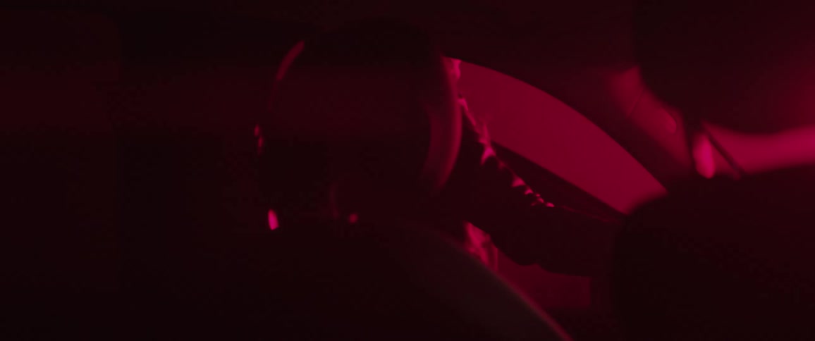 Woman illuminated by red light gets out of her car