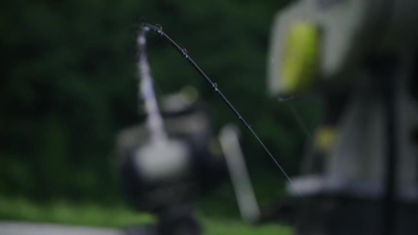 A man's fishing pole is bending in the water