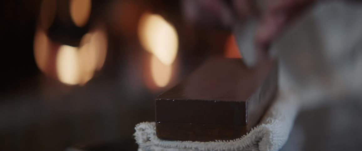 A man sharpens a knife on a block
