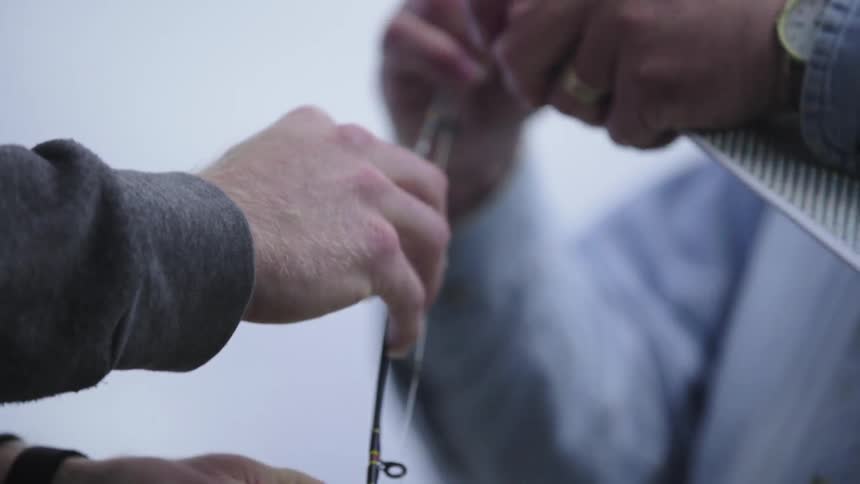 Men attach an object to a fishing pole