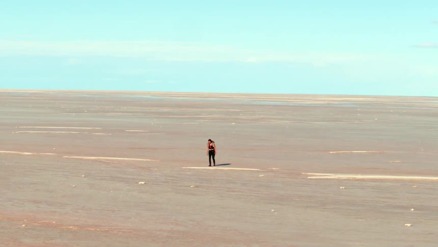 Aerial as a woman hikes alone through a vast desert