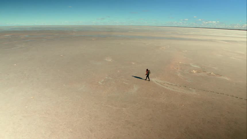 Aerial of a woman walking in a huge desert
