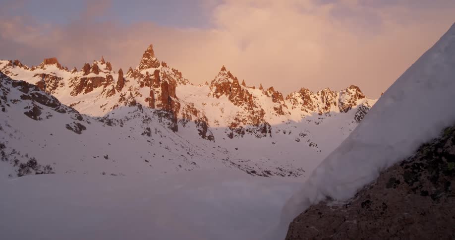 Jagged mountains are covered with snow at sunset