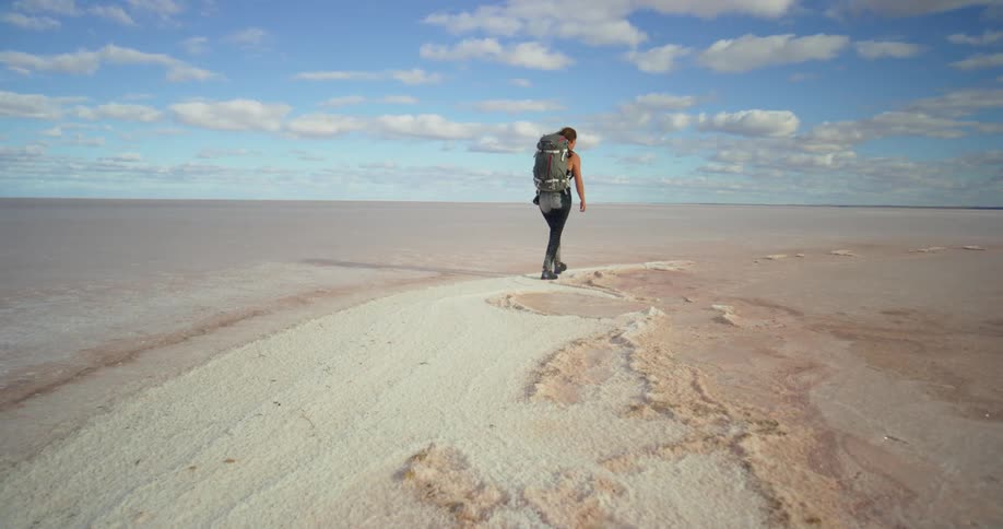 A woman hikes through empty salt flats