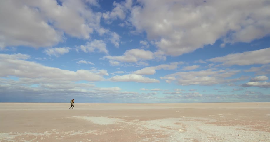 A person with a backpack walking through a vast empty desert