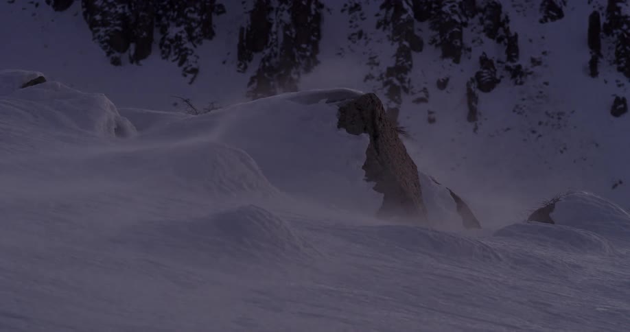 Blowing snow on a mountain at dusk