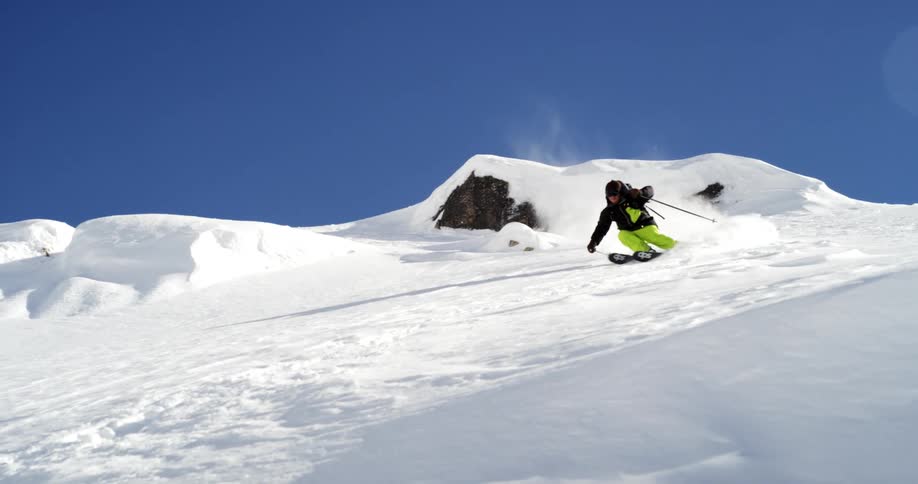 A man jumps and skis down a steep hill