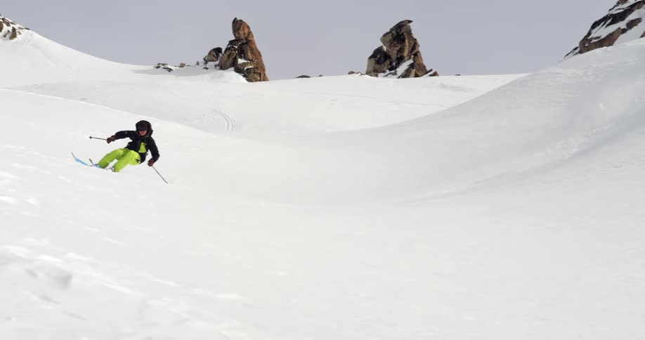 A skier makes wide arcing turns on a slope