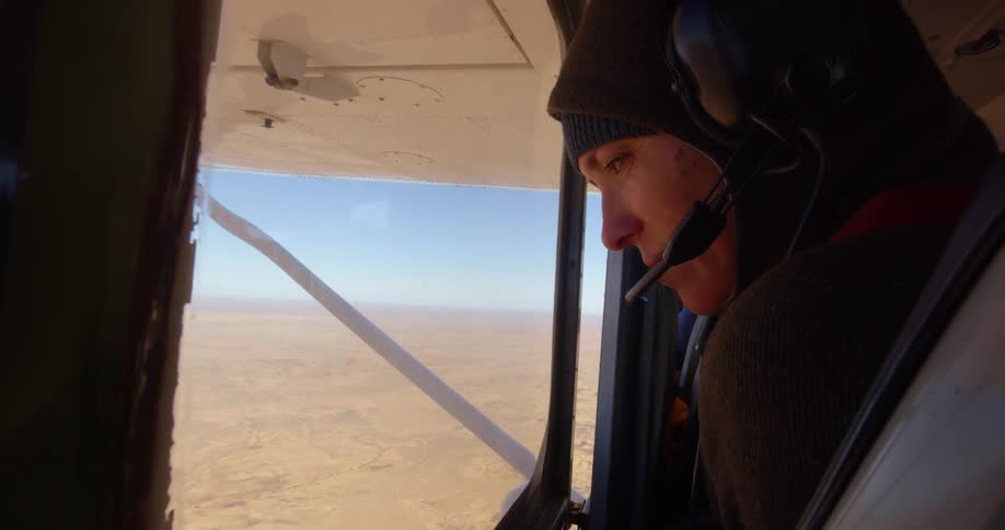 Passenger in a small airplane looks out the window to look at the desert while flying