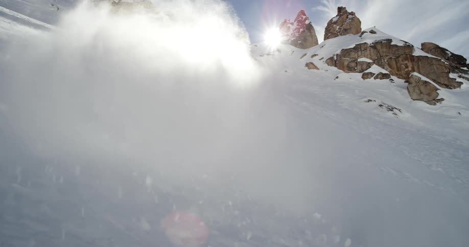 A man skis down a mountain as his dog runs behind him