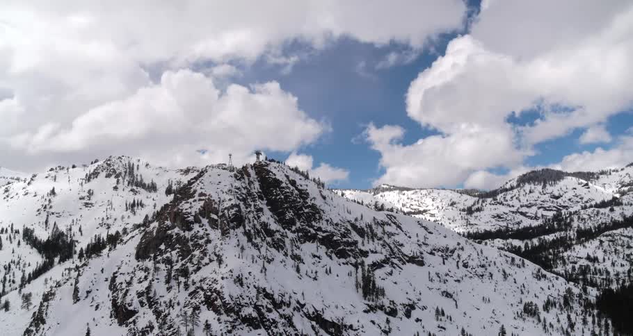 Snow and forests cover mountain sides under cloudy sky