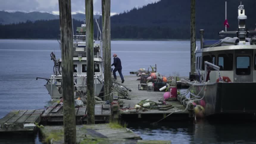 A man walks on a boat holding a bucket