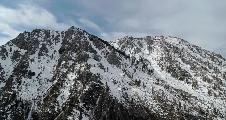 An aerial view of a snowy mountain on a cloudy winter day