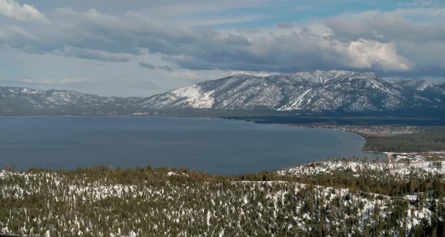 A large lake at the base of a mountain on a sunny day