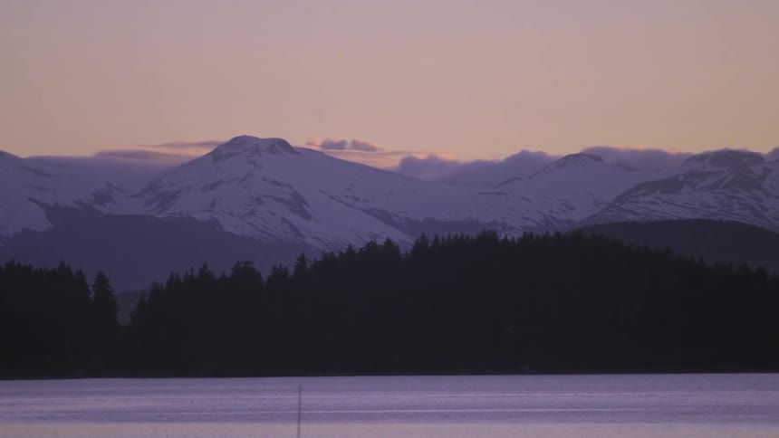A snow capped mountain near a lake at dawn