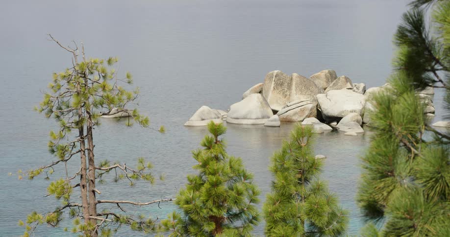 A pile of large rocks in a lake on a sunny day