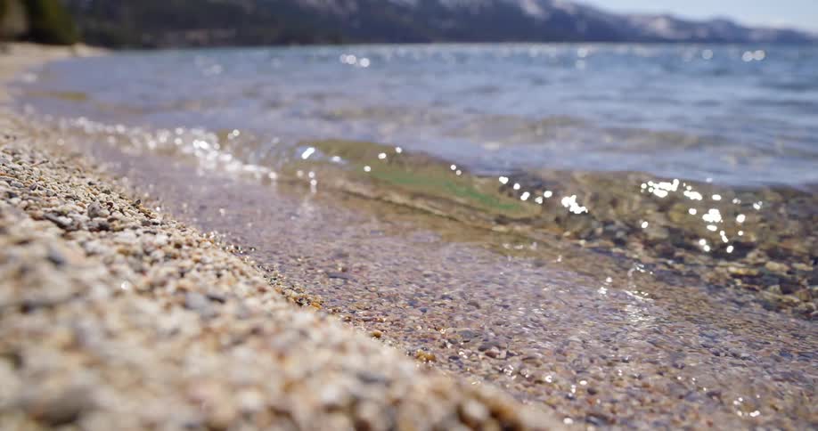 A beach with sand pebbles and water with the sky in the background