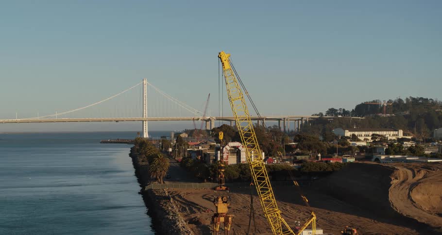 A construction site with cranes on a river bank