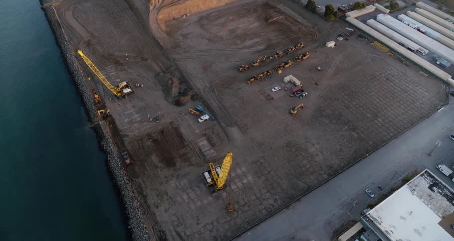 Construction equipment in an empty lot in a warehouse area near a river