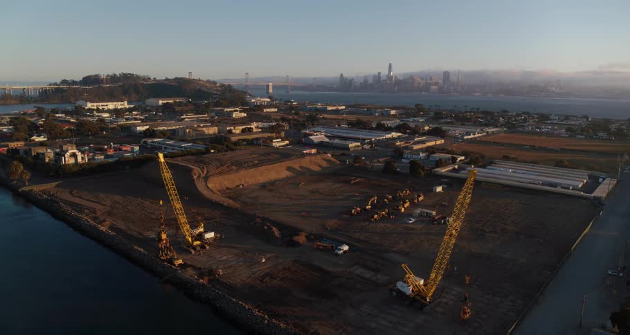 A construction site on a small flat island off the coast of a metropolis