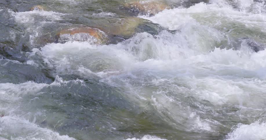 The rapids of a river flowing over rocks during the day
