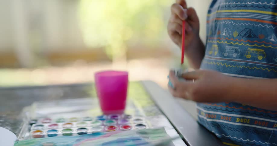 Boy mixes water paints an works on painting