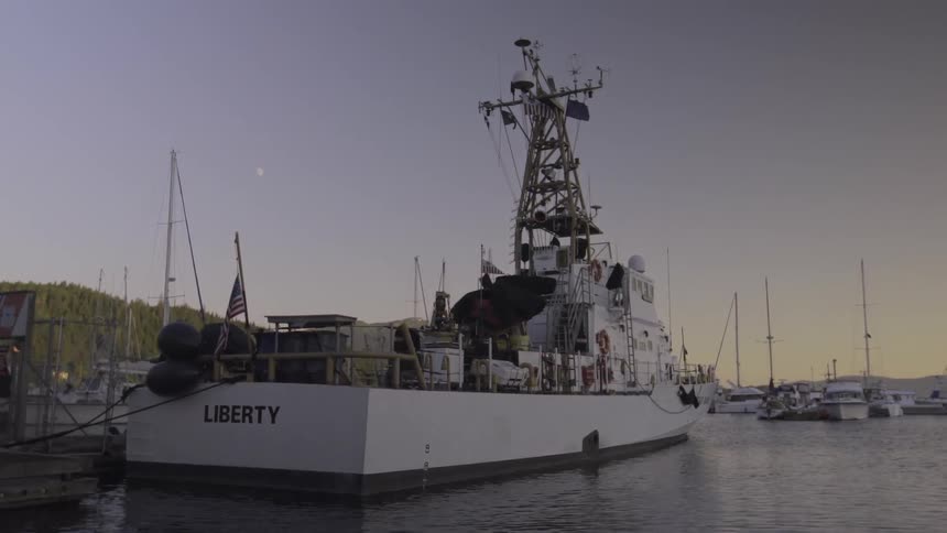 A boat named liberty is docked near sunset